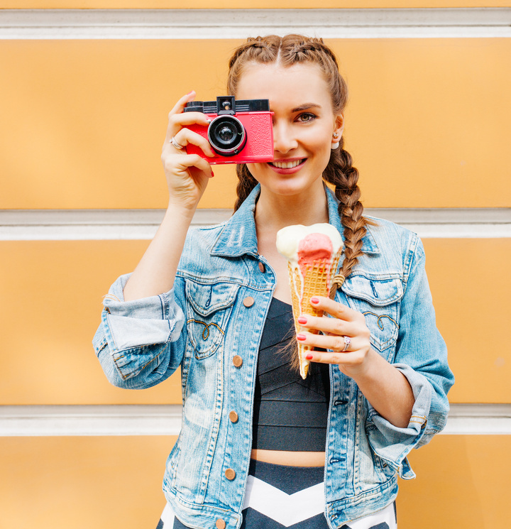 Young woman posing with a camera. Capture the moments of your favorite activities with friends in real life. Invite your friends to your next adventure with buddypassgo.com. 