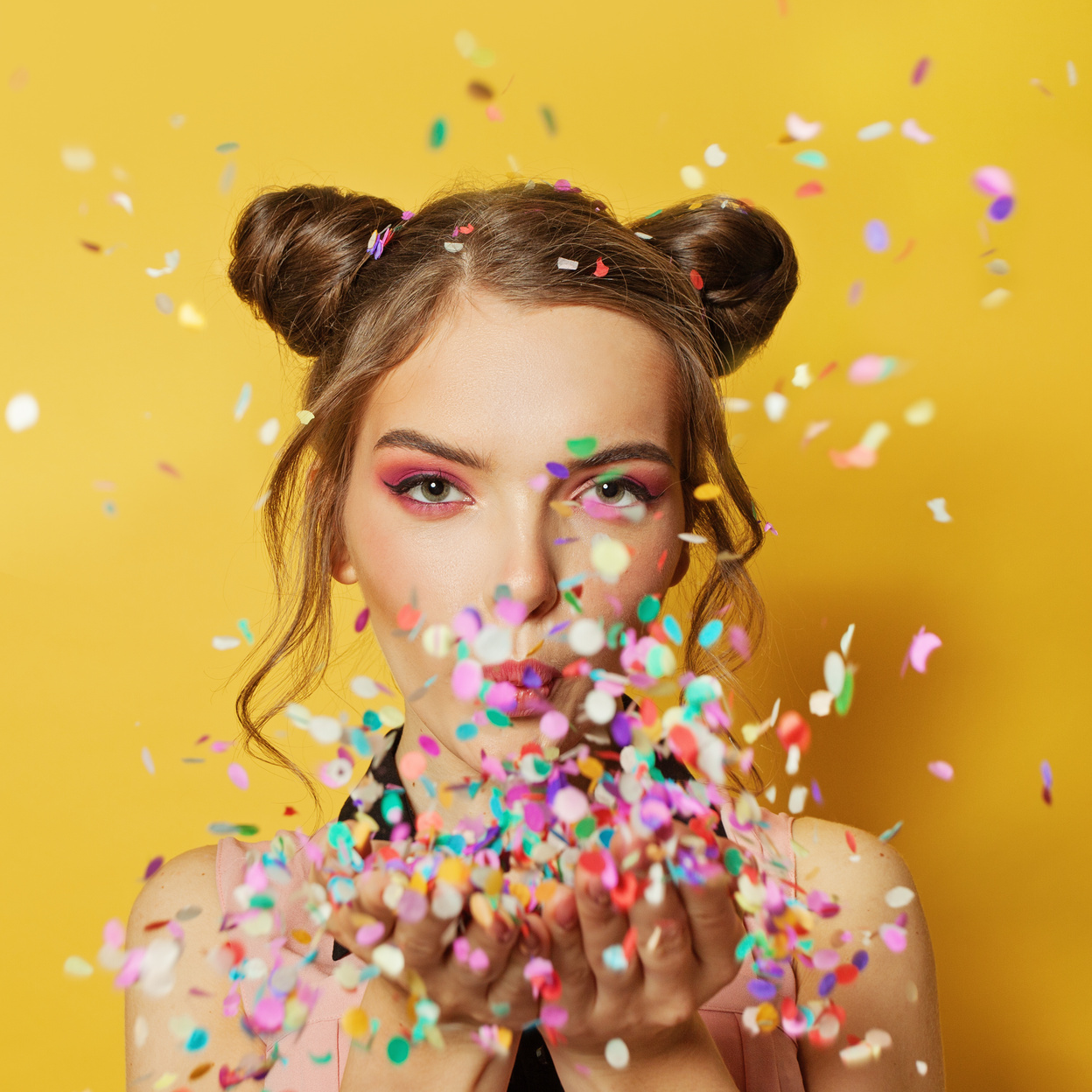 A beautiful woman blowing confetti while celebrating. Find people who want to meet, match, and mingle with you on buddypassgo.com! 